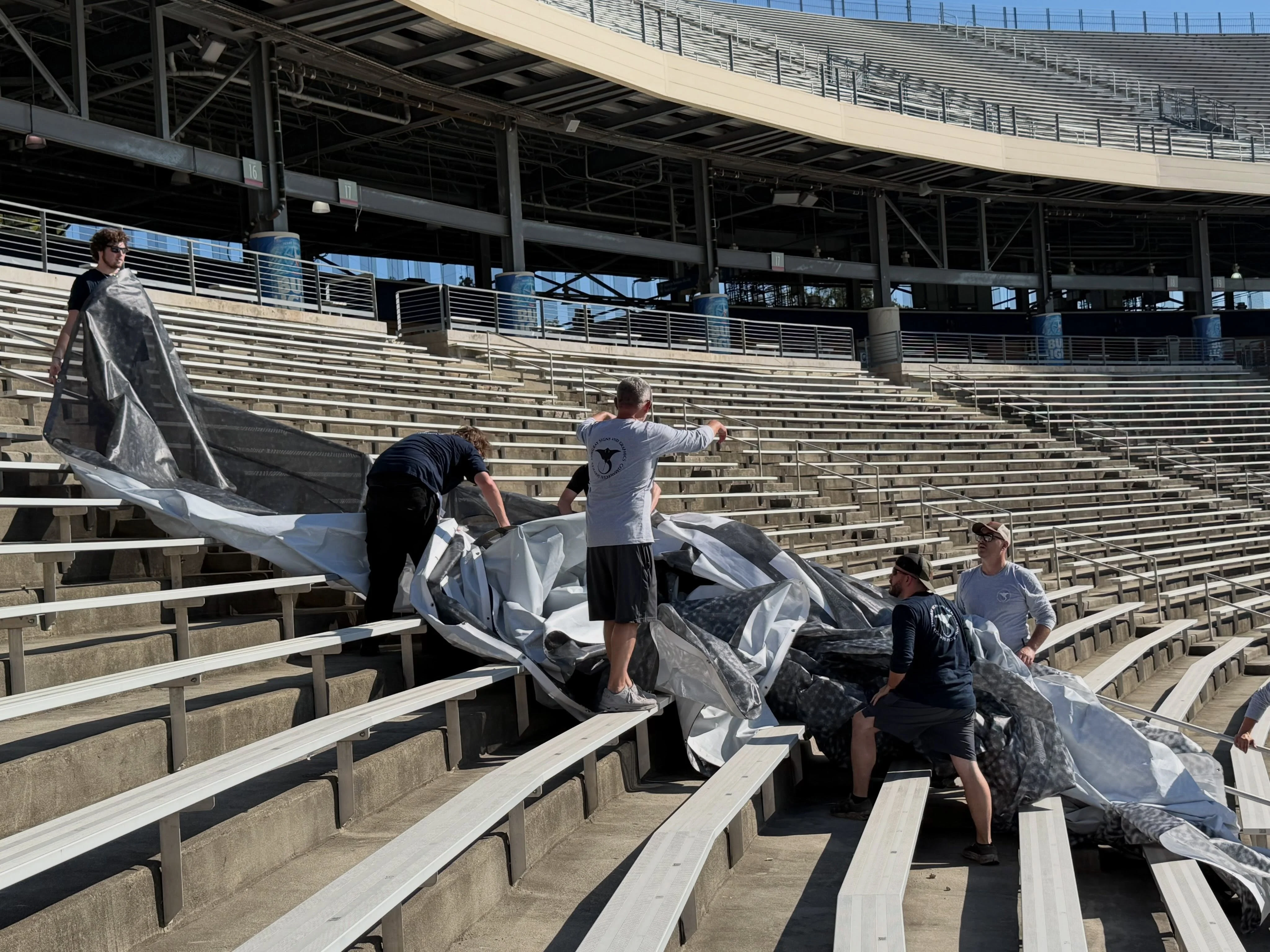 Stingray Signs LLC crew installing massive stadium banners in Cotton Bowl bleachers