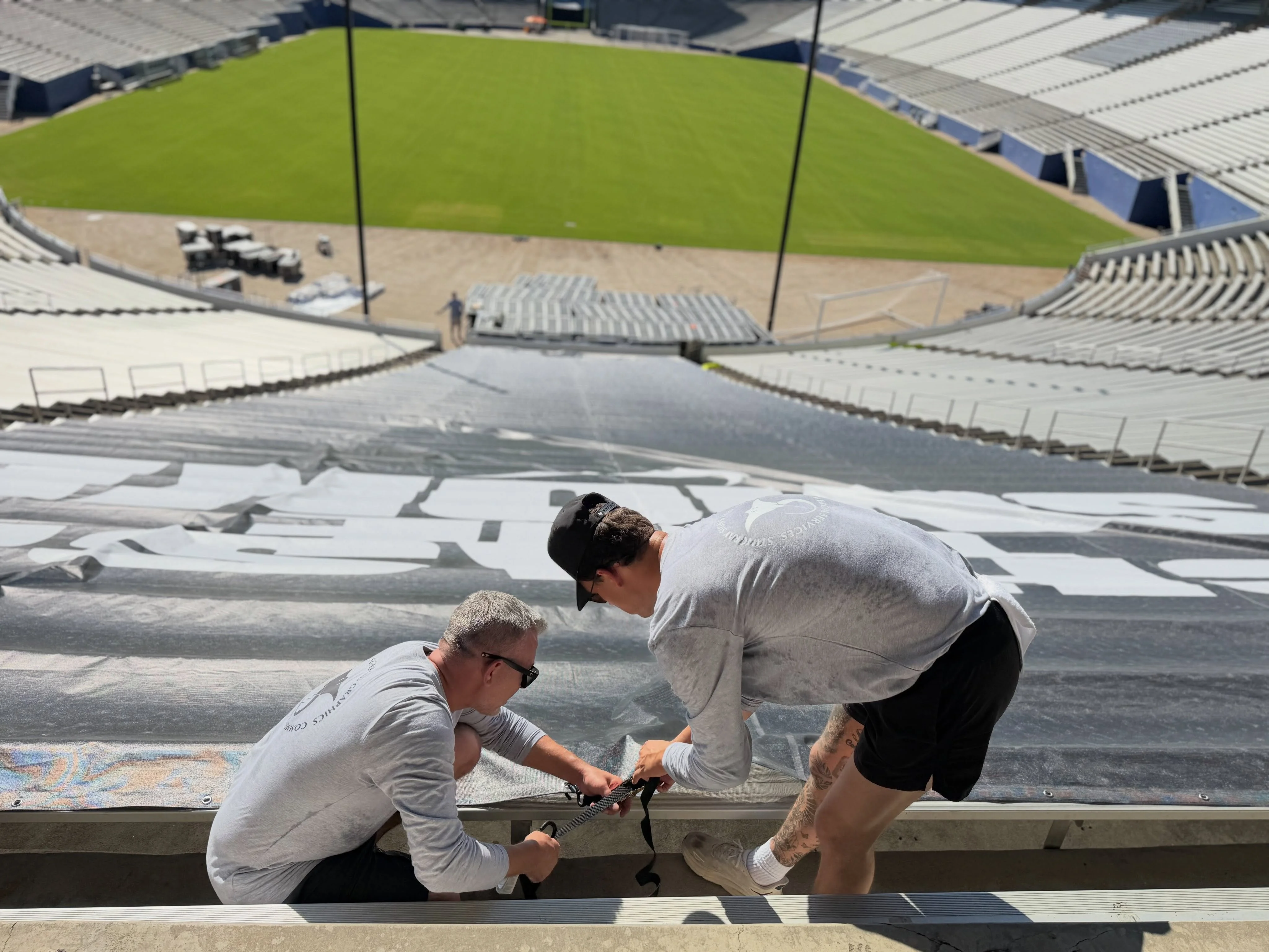 Stingray Signs crew installing Nike Football banner in Cotton Bowl Stadium bleachers